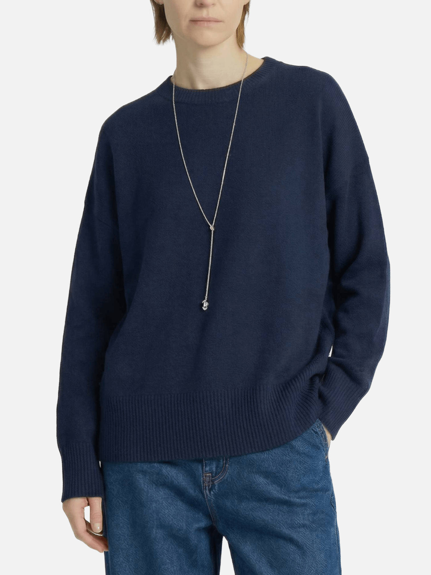 Person wearing a navy sweater and blue jeans on a white background