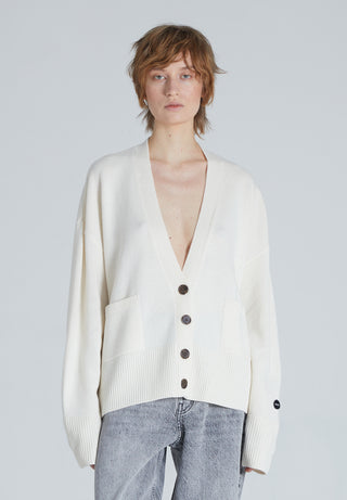Woman wearing a Luxury cashmere cardigan in Cream color, a deep V-neck cardigan with a front button-up closure, front pockets, and ribbed trims. 