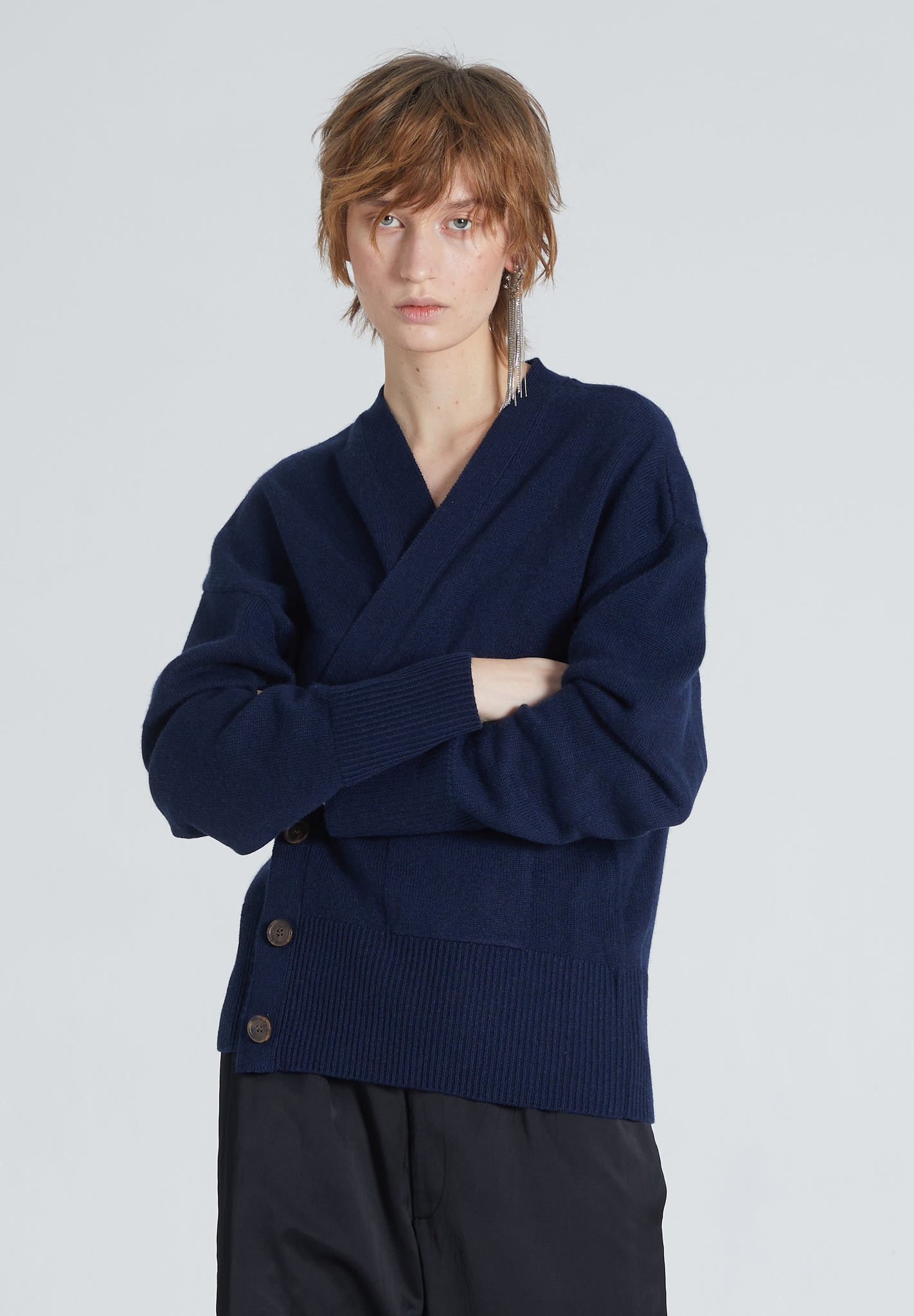 Woman wearing Luxury cashmere cardigan in Navy. Buttoned, timeless, versatile, and sustainable produced. She also wears black pants. 
