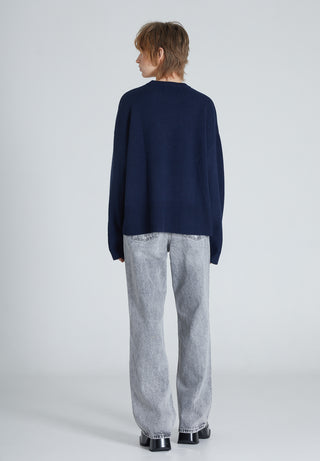 back of woman wearing a dark blue navy cashmere sweater paired with grey jeans and boots